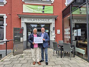 Andreas Fateh und Frank Liebert halten ein Plakat in die Kamera "Wohnen ist Menschenrecht"